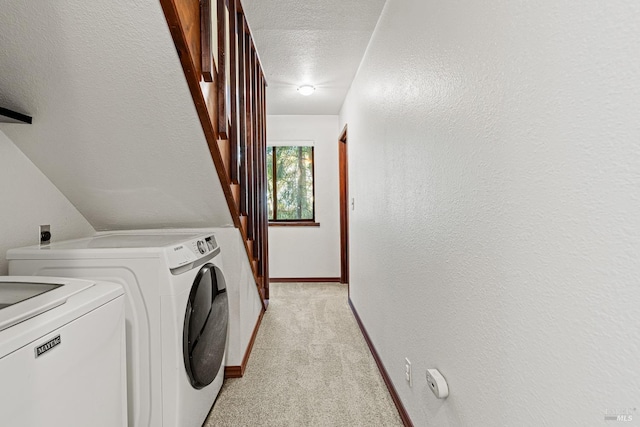 laundry room featuring washing machine and dryer, light colored carpet, and a textured ceiling