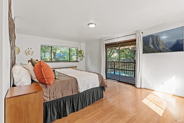 bedroom with access to exterior, light wood-type flooring, and multiple windows