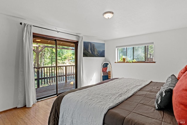 bedroom with access to exterior and hardwood / wood-style floors