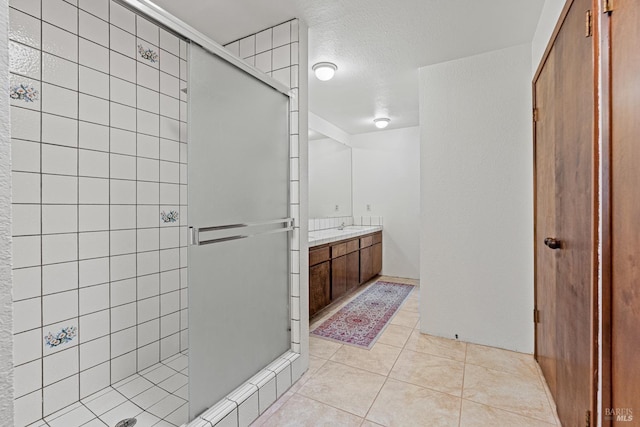 bathroom featuring tile patterned flooring, vanity, a shower with door, and a textured ceiling