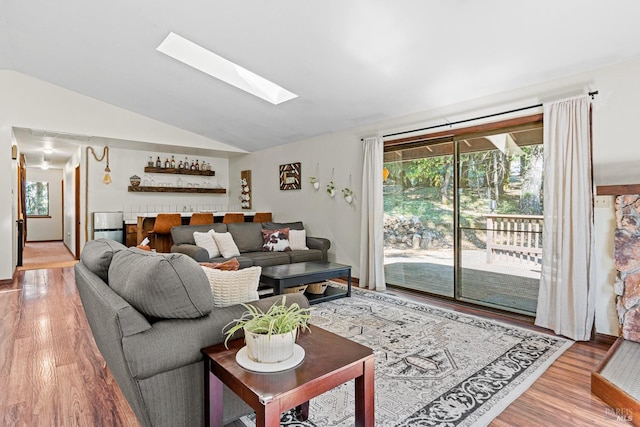 living room with lofted ceiling with skylight and hardwood / wood-style flooring