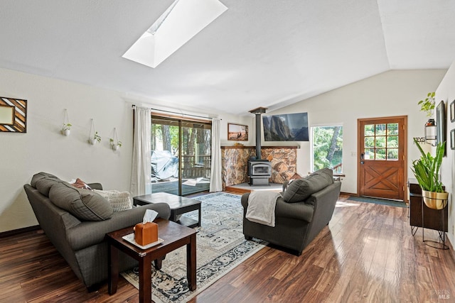 living room featuring vaulted ceiling with skylight, dark hardwood / wood-style flooring, and a wood stove