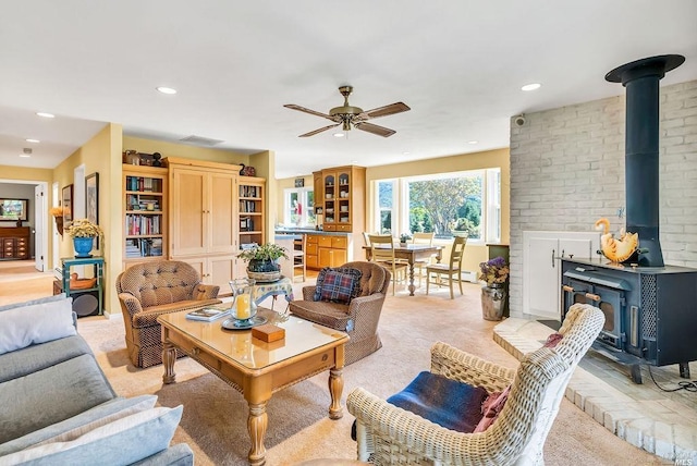 carpeted living room with ceiling fan and a wood stove