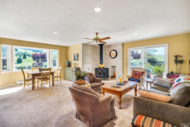 carpeted living room featuring a wealth of natural light and a wood stove