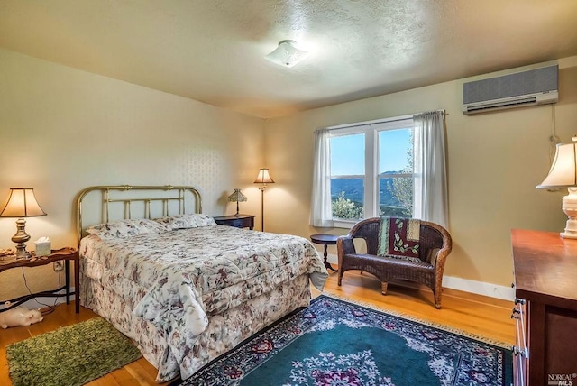 bedroom featuring hardwood / wood-style floors and a wall mounted AC