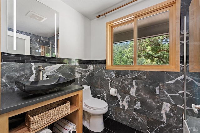 bathroom featuring toilet, a shower, tile walls, vanity, and tile patterned flooring