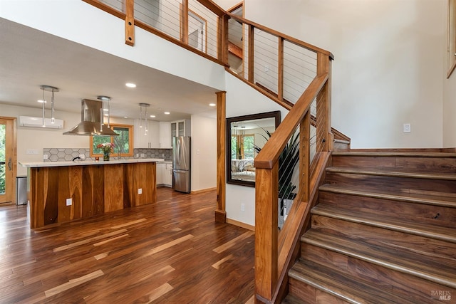 staircase with a high ceiling, a healthy amount of sunlight, and hardwood / wood-style floors