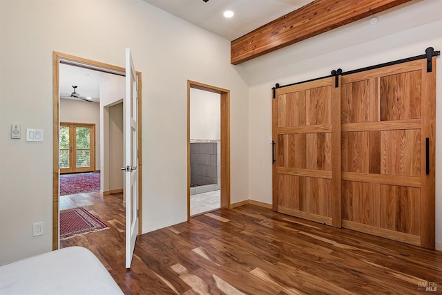 bedroom featuring ensuite bathroom, dark hardwood / wood-style floors, a barn door, beam ceiling, and french doors