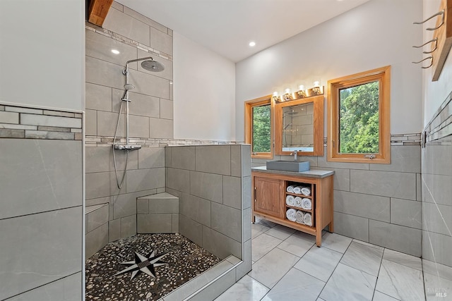 bathroom with tile patterned flooring, vanity, tiled shower, and tile walls