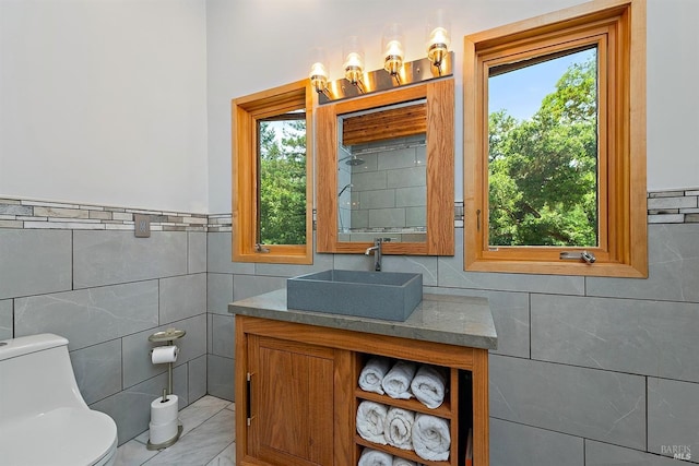 bathroom with vanity, tile walls, and toilet