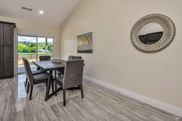 dining area with high vaulted ceiling and light hardwood / wood-style flooring