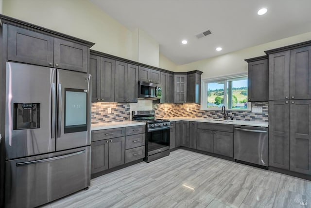 kitchen featuring decorative backsplash, sink, vaulted ceiling, and appliances with stainless steel finishes