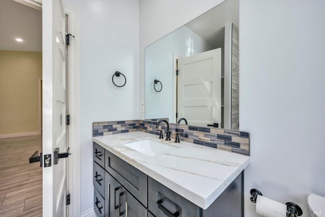 bathroom featuring hardwood / wood-style flooring, vanity, and tasteful backsplash