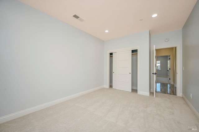 unfurnished bedroom with light carpet and a closet