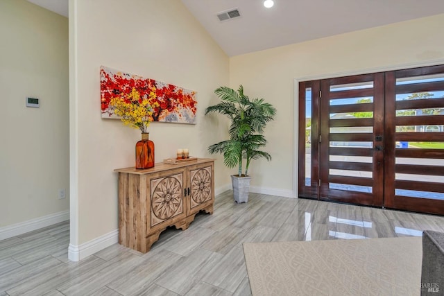 entryway with light hardwood / wood-style floors, lofted ceiling, and french doors