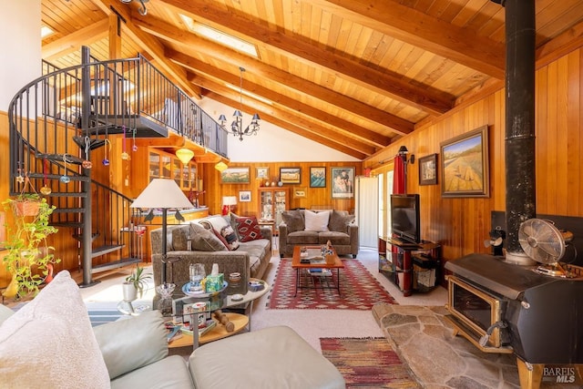 carpeted living room featuring beamed ceiling, a wood stove, and wood walls