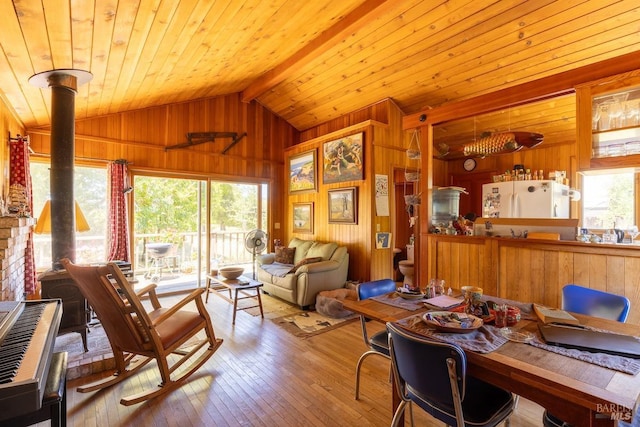 interior space featuring lofted ceiling with beams, light hardwood / wood-style flooring, a healthy amount of sunlight, and wood walls