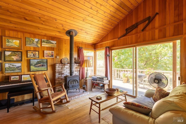 living room featuring wood ceiling, a wood stove, wood walls, and light hardwood / wood-style floors