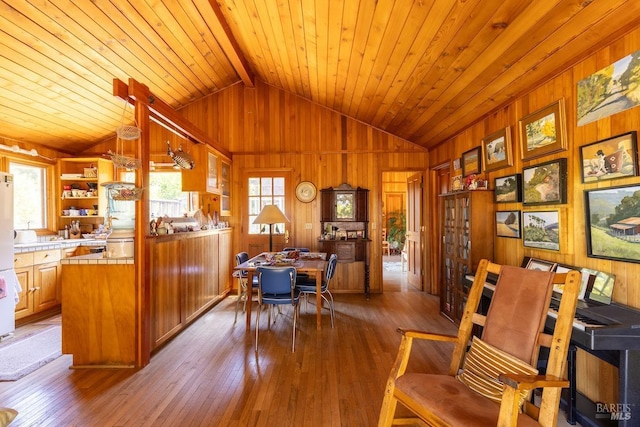 interior space with lofted ceiling with beams, wood walls, wooden ceiling, and light hardwood / wood-style flooring