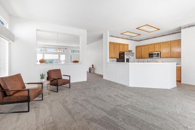 interior space featuring kitchen peninsula, a chandelier, light colored carpet, and stainless steel appliances