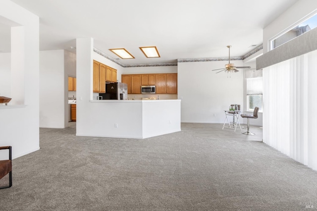 kitchen with ceiling fan, light colored carpet, kitchen peninsula, and appliances with stainless steel finishes