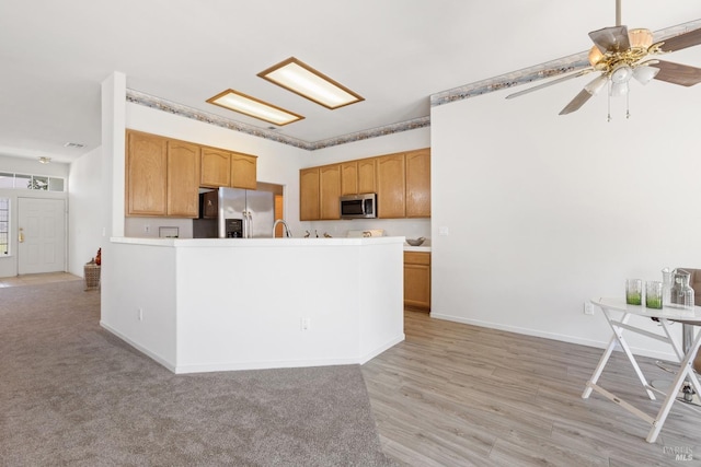 kitchen featuring light countertops, appliances with stainless steel finishes, a ceiling fan, a peninsula, and baseboards