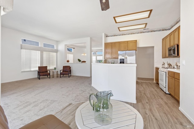 interior space with white gas range, light countertops, stainless steel microwave, open floor plan, and refrigerator with ice dispenser