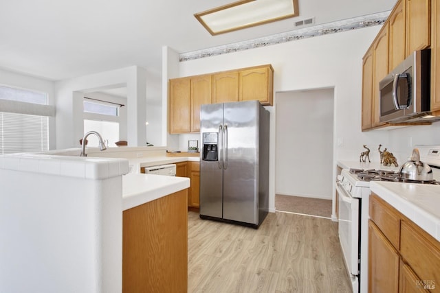 kitchen with visible vents, tile countertops, appliances with stainless steel finishes, a peninsula, and light wood-style floors