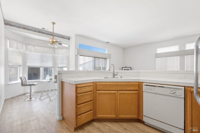 kitchen featuring white dishwasher, ceiling fan, sink, and light hardwood / wood-style flooring