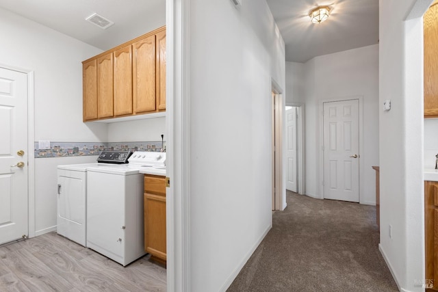 washroom with washer and dryer, cabinets, and light carpet