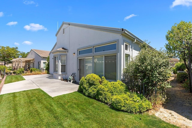 back of house featuring a lawn and a patio