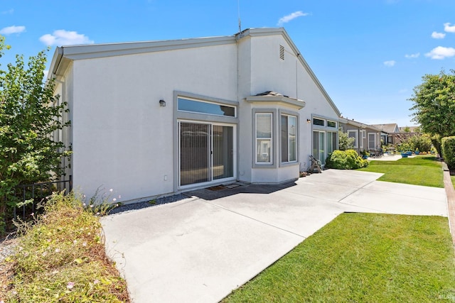 rear view of property with a lawn and a patio area