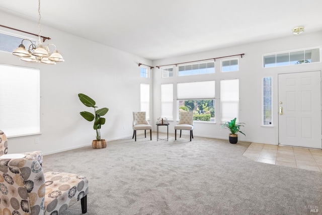 living area featuring baseboards, carpet flooring, and a notable chandelier