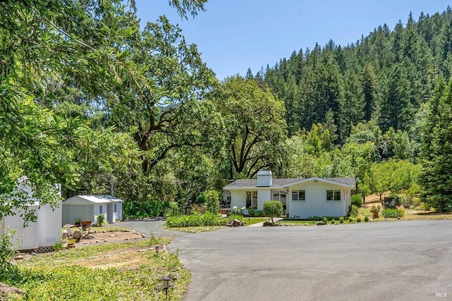5135 Dry Creek Rd, Napa, CA 94558 - view of front of house featuring an outdoor structure, a forest view, and a chimney