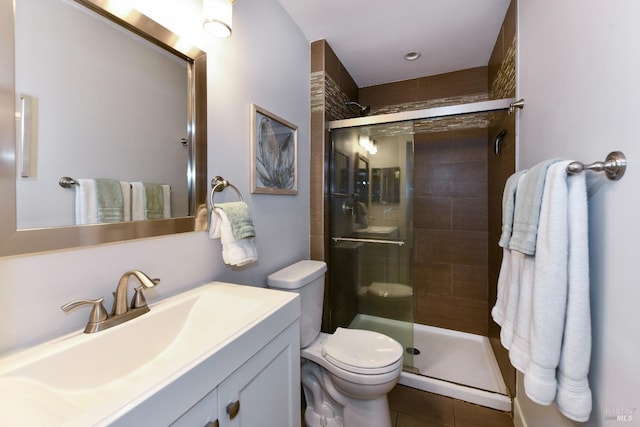 bathroom with tile patterned floors, a shower with door, vanity, and toilet