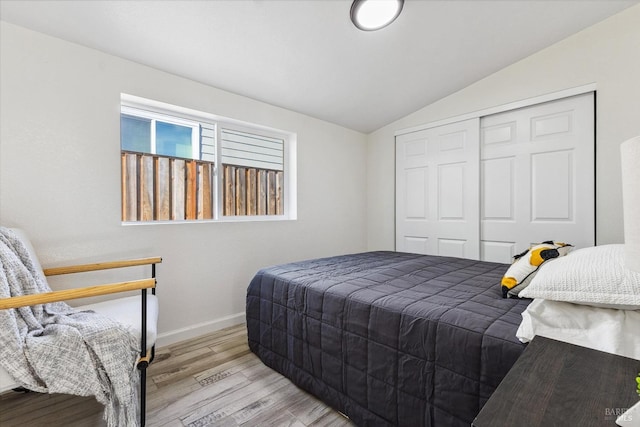 bedroom with a closet, vaulted ceiling, and light hardwood / wood-style flooring