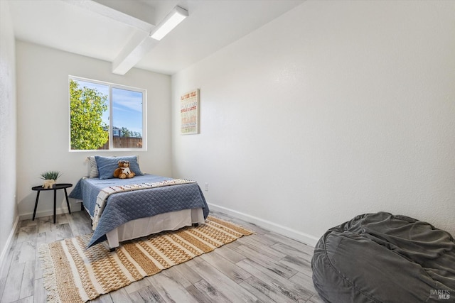 bedroom with beamed ceiling and light hardwood / wood-style floors