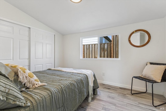 bedroom with lofted ceiling, a closet, and light wood-type flooring