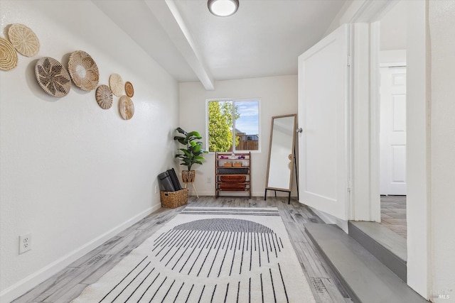 hallway featuring beamed ceiling and light wood-type flooring