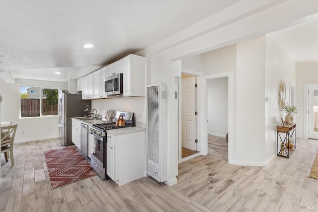 kitchen featuring appliances with stainless steel finishes, sink, white cabinets, and light hardwood / wood-style floors