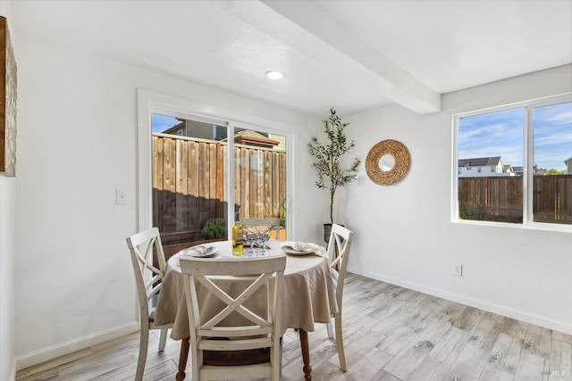 dining space featuring beam ceiling and light hardwood / wood-style floors