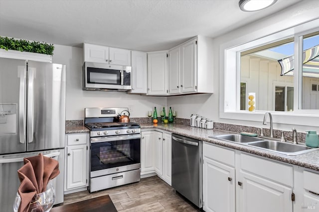 kitchen with white cabinetry, appliances with stainless steel finishes, light hardwood / wood-style floors, and sink