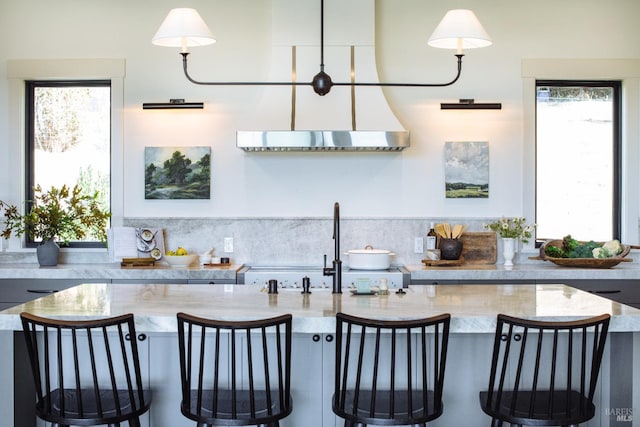 kitchen with decorative light fixtures, light stone countertops, and plenty of natural light