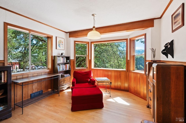 living area featuring wood walls, ornamental molding, and light hardwood / wood-style flooring