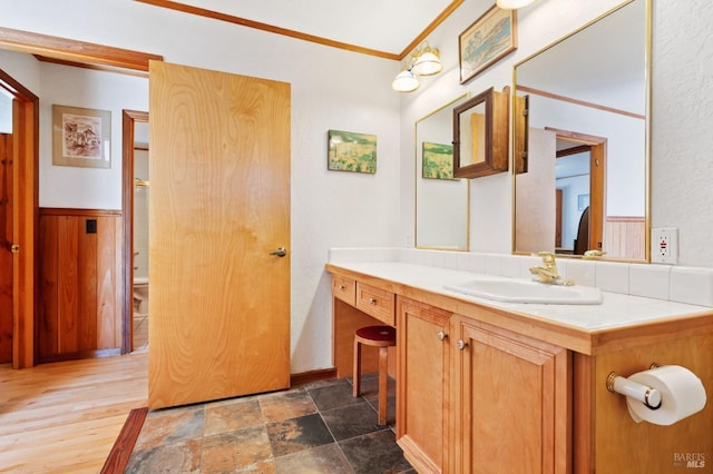 bathroom with toilet, vanity, wood walls, and ornamental molding