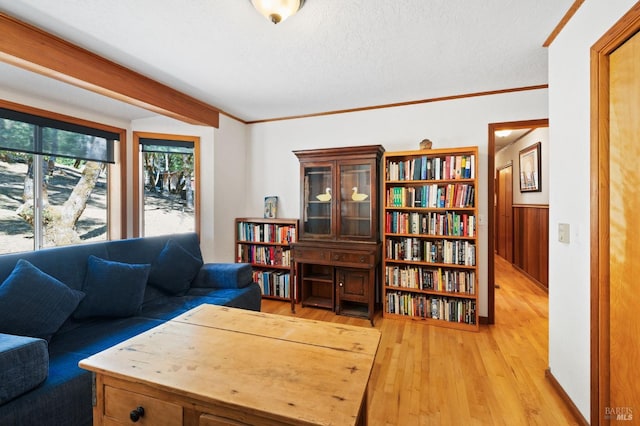 living room featuring wooden walls, a textured ceiling, and light hardwood / wood-style floors