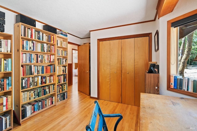 interior space featuring a textured ceiling, crown molding, and light hardwood / wood-style flooring