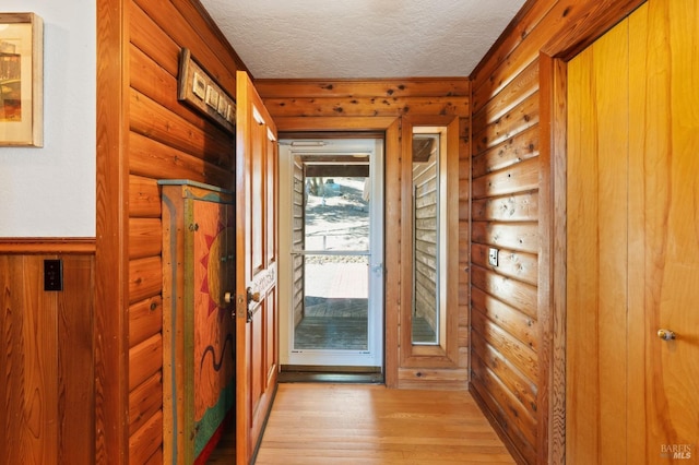 doorway featuring light hardwood / wood-style floors, a textured ceiling, and log walls