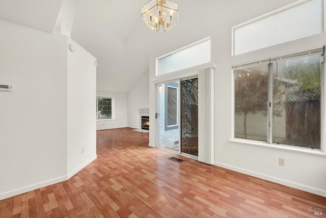 unfurnished living room with a chandelier, light hardwood / wood-style floors, and vaulted ceiling