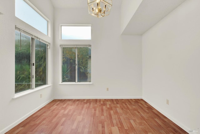 unfurnished room with an inviting chandelier and light wood-type flooring